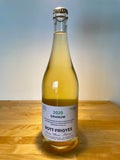 Bott Frigyes Granum with a light shining down on the bottle showcasing a cloudy white wine